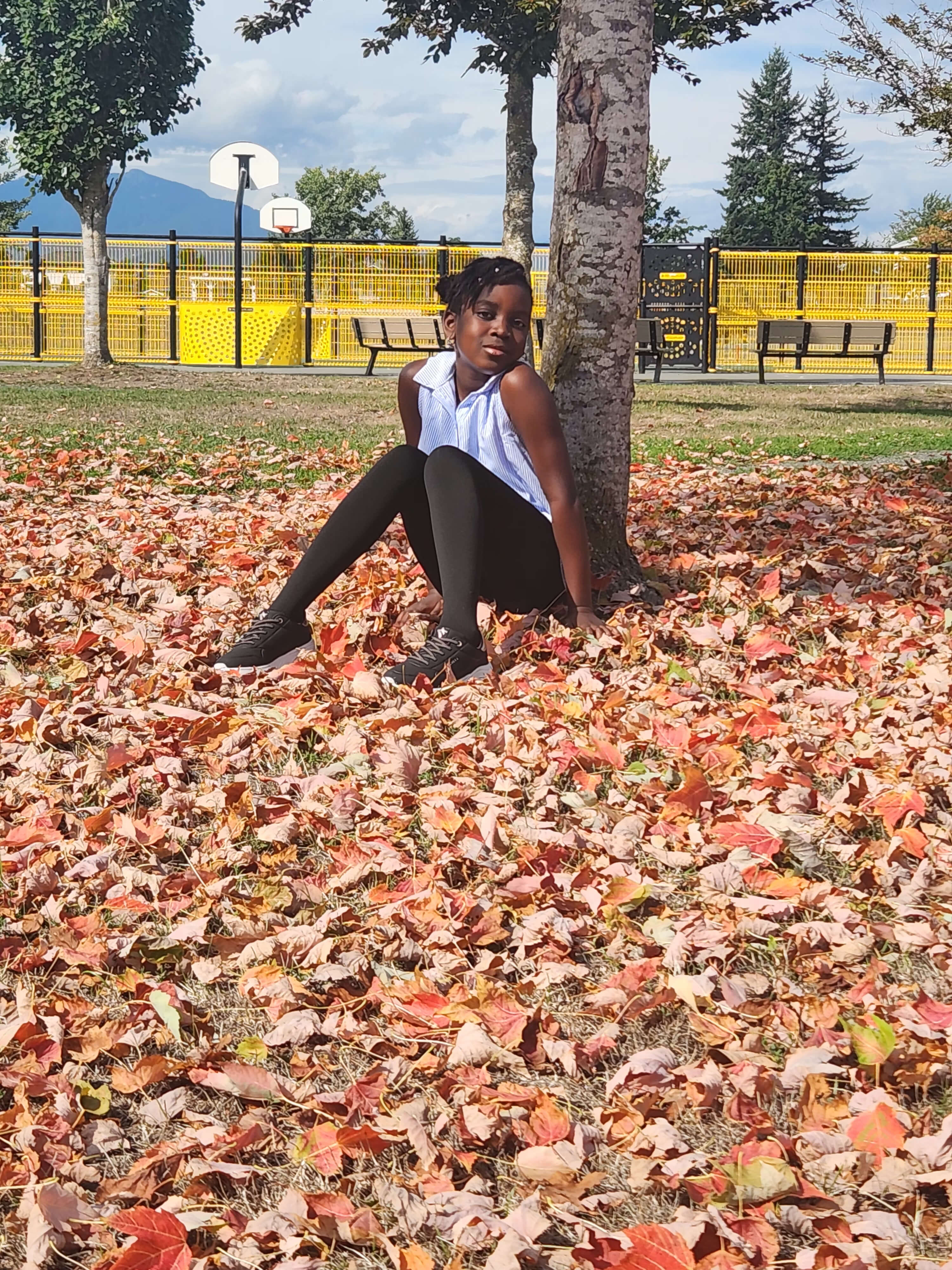 Jemima Adumeta sitting among autumn leaves in a park